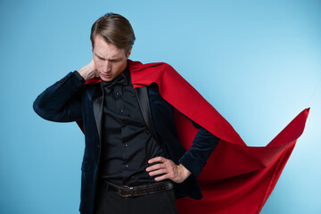 The superhero feels tired and insecure. Impostor syndrome in professionals, concept. A man in a business suit and a red cape.