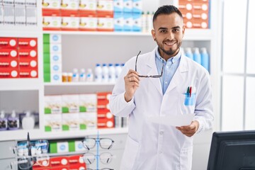 Young hispanic man pharmacist holding prescription working at pharmacy