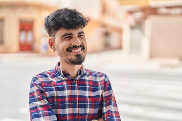 Young hispanic man smiling confident looking to the side at street