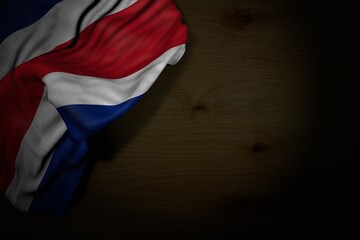 beautiful dark picture of Costa Rica flag with large folds on dark wood with free space for your text - any holiday flag 3d illustration..