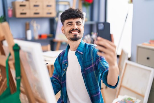 Young hispanic man artist make selfie by smartphone drawing at art studio