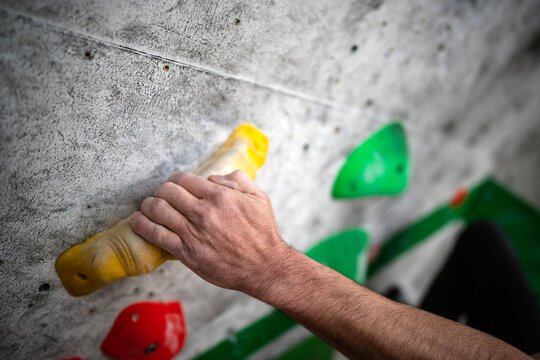 Male hand smeared with magnesium powder grabbing a hold of a climbing wall