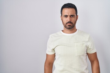 Hispanic man with beard standing over isolated background skeptic and nervous, frowning upset because of problem. negative person.