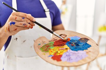 Young hispanic man mixing color on palette at art studio