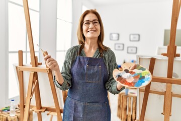 Middle age artist woman smiling happy painting at art studio