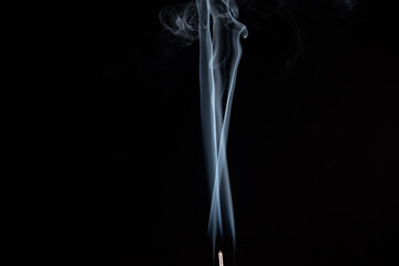 incense stick with smoke against black background