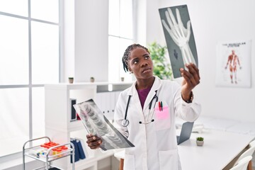 African american woman wearing doctor uniform looking xray at clinic