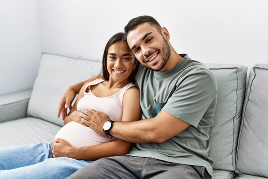 Latin man and woman couple hugging each other expecting baby at home
