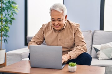 Senior man using laptop sitting on sofa at home