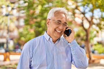 Senior man smiling confident talking on the smartphone at park