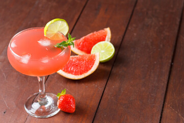 Fresh grapefruit juice in a glass with grapefruit pieces, lime and mint on a wooden background. copy space