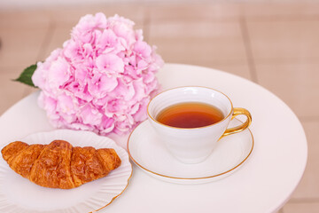 
Cup of tea and croissants with hydrangea flower on white background
