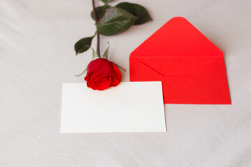 
Red rose and envelope with copy space, laying on white bed. Valentine's day background, love and romance.