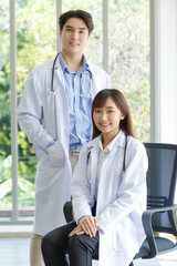 Medicine and healthcare concept : Happy and cheerful asian doctors, Male and Female  arms with stethoscope and smiling in lobby of hospital.