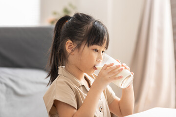 Happy Asian Kid drinking fresh milk for good health at home.Enjoy and tasty for strong bone.Female...