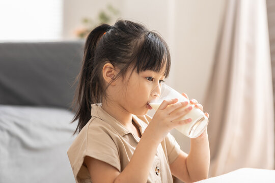 Happy Asian Kid Drinking Fresh Milk For Good Health At Home.Enjoy And Tasty For Strong Bone.Female Kid Drink Soy Milk From Glass Tasty And Delicious With Calcium.Healthy Lifestyle Concept