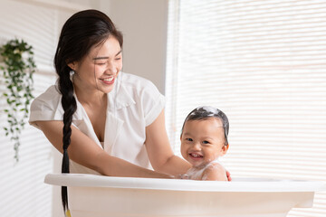 Calm asian baby bathing in bathtub enjoy laughing. mother bathing her son in warm water.Happy...