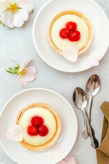 Delicious red raspberry strawberry whipped creamy tartlets,cakes.gourmet confection dessert on plate with latte coffee,milk.sweet tasty pastry baked pie cheesecake with ripe berries on gray table