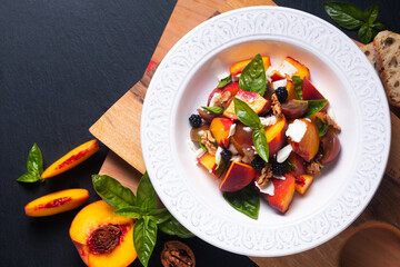 Healthy food concept Tomato Peach Salad with Basil and Goat Cheese on wooden board on black background with copy space