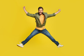 Fototapeta na wymiar Expressing happiness. Full length studio shot of excited middle aged man jumping over yellow background