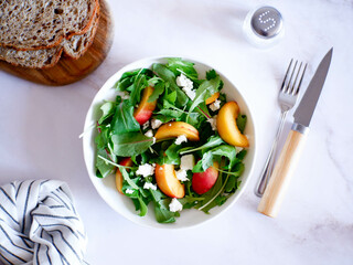 A light summer salad of rucolla, peaches and cheese on a light background.