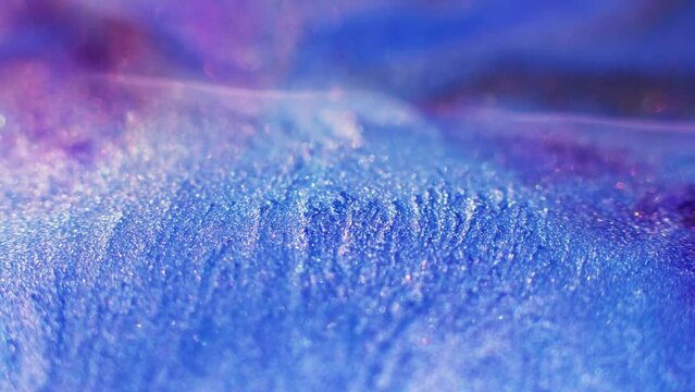 Bokeh glitter background. Sparkling ink. Fantasy waterfall. Defocused neon blue purple pink color shiny sequin scattering abstract grain texture.