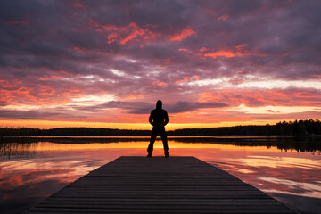 silhouette of a person standing on the pier at sunrise
