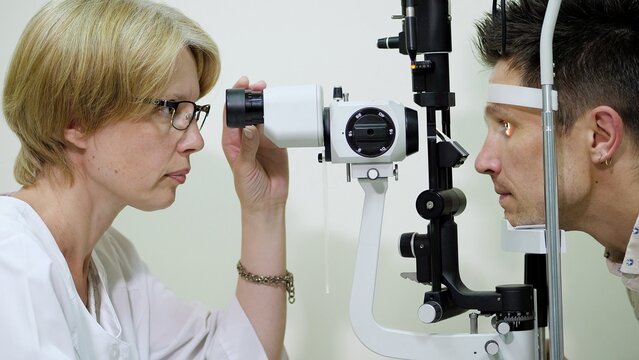 female doctor optometrist, ophthalmologist with non contact tonometer is cheking patient's vision, intraocular pressure at eye clinic or optics store, ophthalmilogical laboratory. High quality photo
