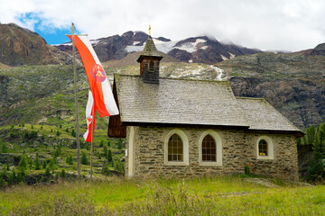 Mountain chapel on an alpine meadow in sudtirol with mountain range in the background