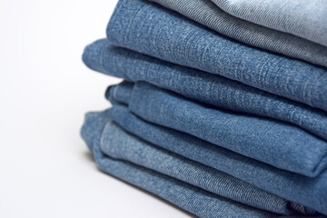 Lots of jeans pants in a stack. Denim background.