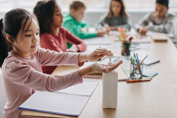 Japanese Schoolgirl Disinfecting Hands During Class At School