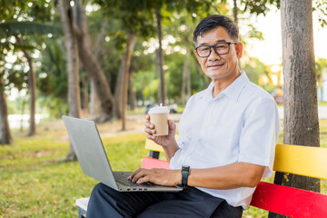 Senior man using the laptop and happy drink coffee at the park, lifestyle senior concept