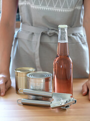Fototapeta na wymiar hostess in a gray kitchen apron demonstrates a bottle and can opener
