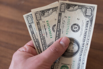 mano con billetes de 100 dolares americanos sobre fondo marron madera