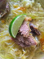 Close up beef soto (indonesian food) served with beef, rice noodle, rice, and lime