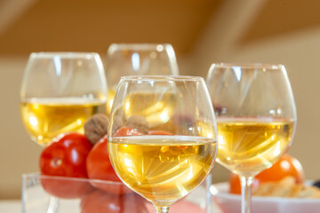 crystal glasses filled with white wine and a bowl filled with ripe tomatoes