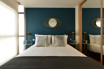 Bedroom with double bed with bright gray cushions, indigo blue wall, built-in wardrobe with sliding...