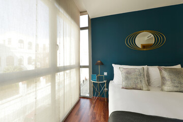 Bedroom with double bed with bright gray cushions, indigo blue wall, built-in wardrobe with sliding...
