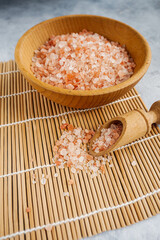 pink Himalayan salt in a wooden bowl on a gray background