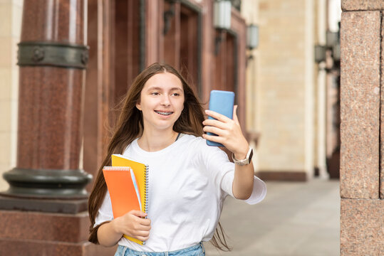 a beautiful student girl with braces smiles talks on the phone with friends, a teenager holds notebooks and children go to college at a lecture