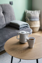 Fototapeta na wymiar cup of tea and teapot on coffee table in living room