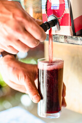 man pouring wine in glass from bag in box close up