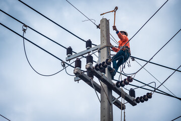 Asian electricians are climbing on electric poles to install and repair power lines.