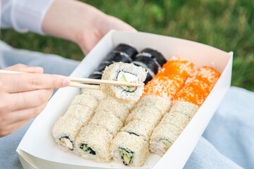 Close up of sushi in box at picnic, sushi delivery concept.