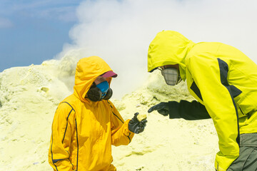 volcanologists on the slope of the volcano examines samples of minerals against the backdrop of...