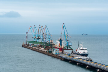 cargo berth with port cranes and moored ships against the backdrop of the open sea