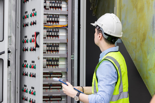 Electrical engineer working in control room. Electrical engineer man checking Power Distribution Cabinet in the control room	