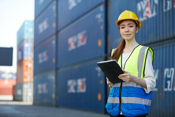 factory worker or engineer holding tablet for work in containers warehouse storage