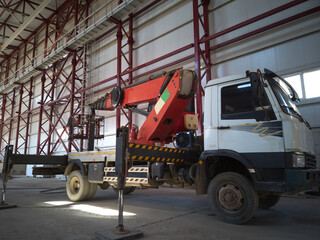 Aerial platform lift. Mobile construction crane inside of industrial building. Telehandler with outriggers stands inside of hangar