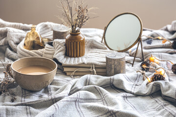 Cozy autumn composition with a cup of coffee and candles in bed.